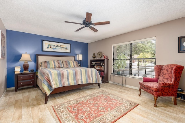bedroom with a textured ceiling, ceiling fan, wood finished floors, and baseboards