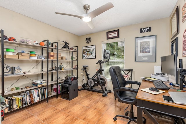 office with a textured ceiling, ceiling fan, and light wood-type flooring