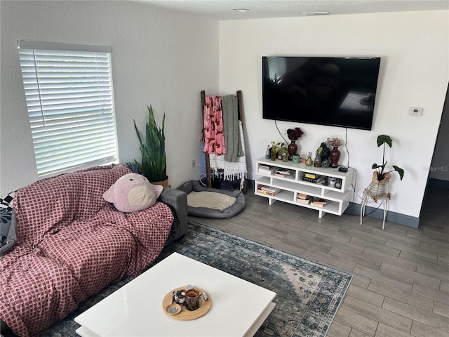 living room with wood finish floors, visible vents, and baseboards