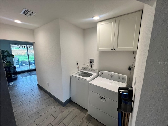 laundry room featuring visible vents, cabinet space, wood tiled floor, washer and dryer, and baseboards