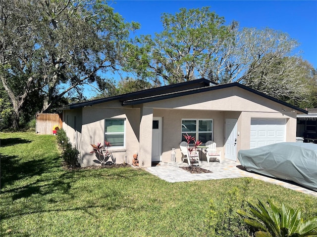 rear view of property featuring a patio area, a yard, and stucco siding