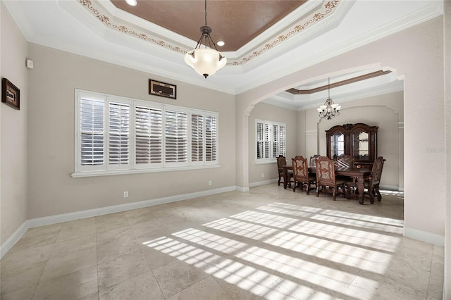 dining space with arched walkways, baseboards, an inviting chandelier, a raised ceiling, and crown molding