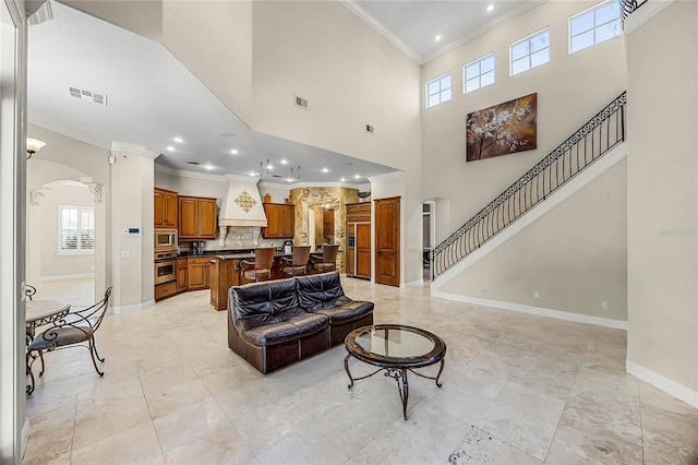 living area with arched walkways, a healthy amount of sunlight, visible vents, and crown molding