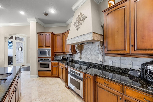 kitchen featuring visible vents, appliances with stainless steel finishes, custom exhaust hood, tasteful backsplash, and dark stone countertops