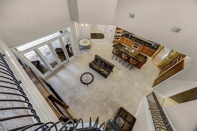 living area featuring stairs, a towering ceiling, visible vents, and an inviting chandelier