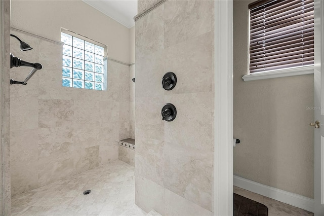 bathroom featuring baseboards, ornamental molding, and a tile shower