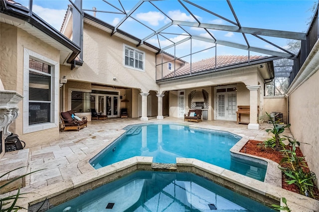 view of pool with french doors, a patio area, a pool with connected hot tub, and a lanai