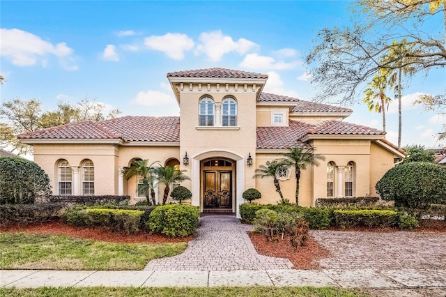 mediterranean / spanish house with stucco siding, french doors, and a tiled roof