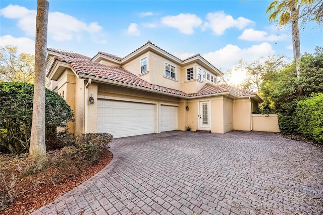 mediterranean / spanish-style home with decorative driveway, a tile roof, and stucco siding