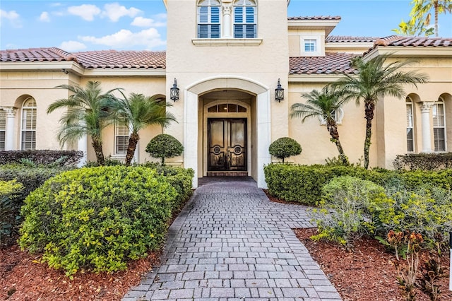 doorway to property featuring a tiled roof and stucco siding