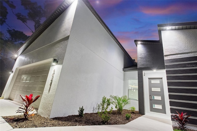 property entrance featuring a garage and stucco siding