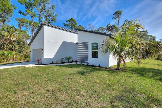 view of side of property with driveway, a lawn, an attached garage, and stucco siding