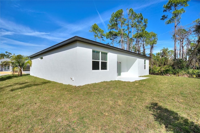 view of side of home with a lawn and stucco siding