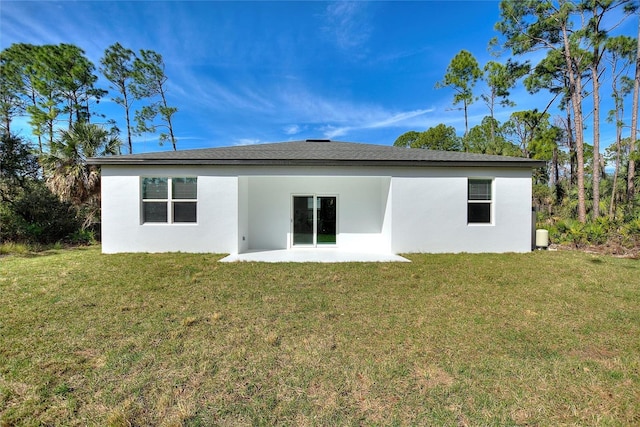 rear view of house featuring a patio, a lawn, and stucco siding