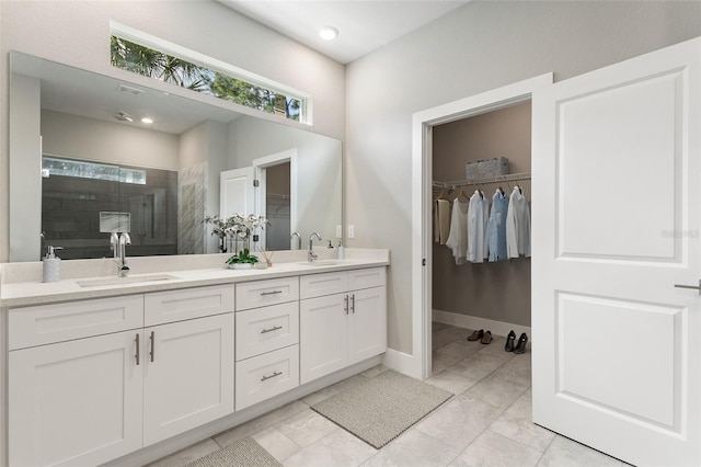 full bath featuring double vanity, a walk in closet, a sink, and a walk in shower