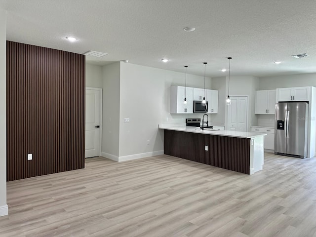2246 SW 167th Pl, Ocala, FL 34475 - kitchen featuring stainless steel appliances, light countertops, a peninsula, a textured ceiling, and light wood-style flooring