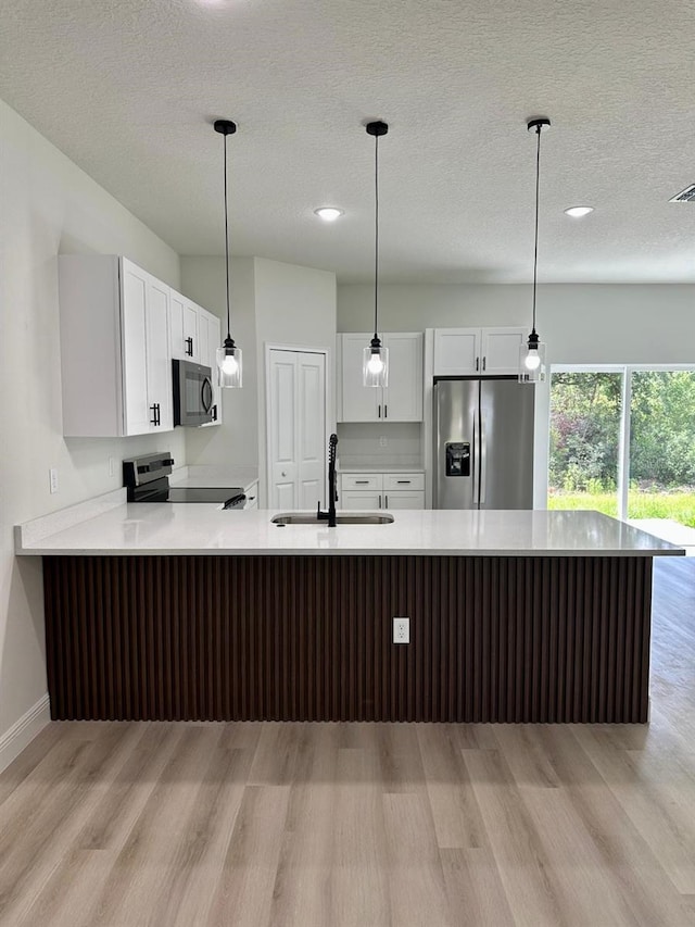 2246 SW 167th Pl, Ocala, FL 34475 - kitchen featuring appliances with stainless steel finishes, light wood finished floors, a peninsula, light countertops, and white cabinetry