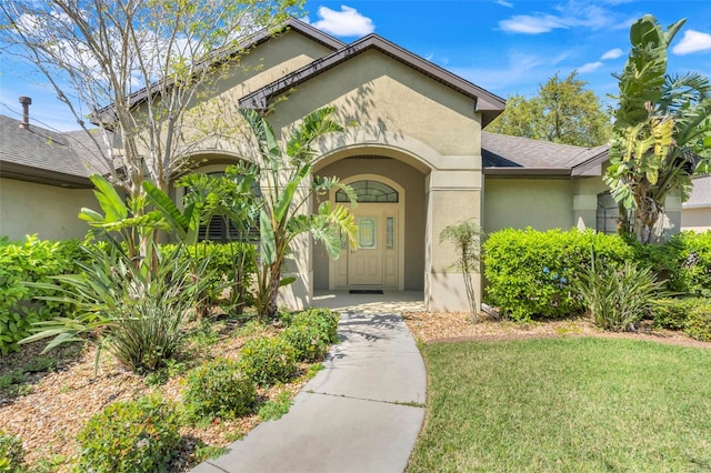 doorway to property with stucco siding and a lawn