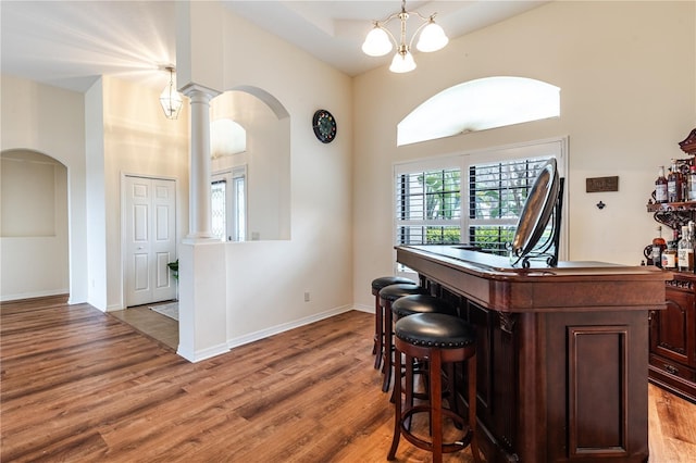 bar featuring wood finished floors, arched walkways, and baseboards