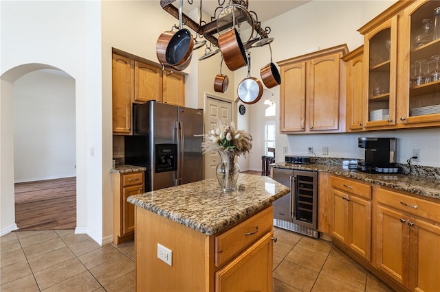 kitchen with wine cooler, stainless steel fridge, arched walkways, and light tile patterned floors