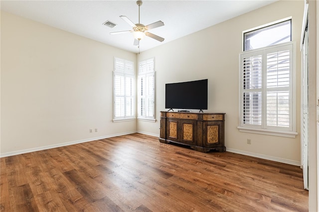 unfurnished living room featuring visible vents, baseboards, a ceiling fan, and wood finished floors