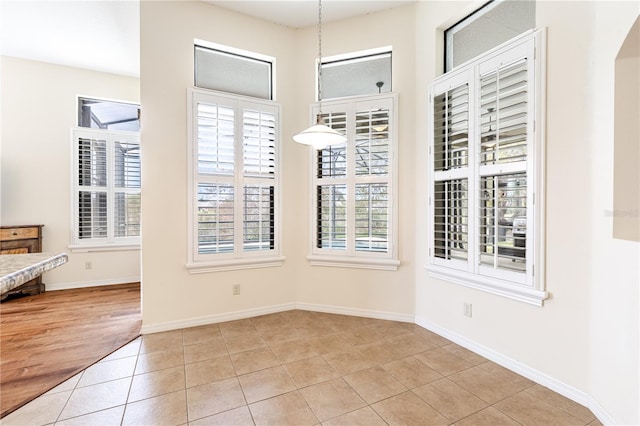 unfurnished dining area featuring light tile patterned floors and baseboards