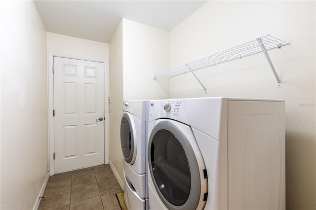 washroom featuring washing machine and clothes dryer, laundry area, tile patterned flooring, and baseboards