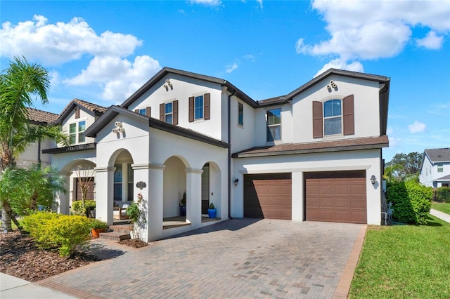 view of front facade with a garage, decorative driveway, and stucco siding