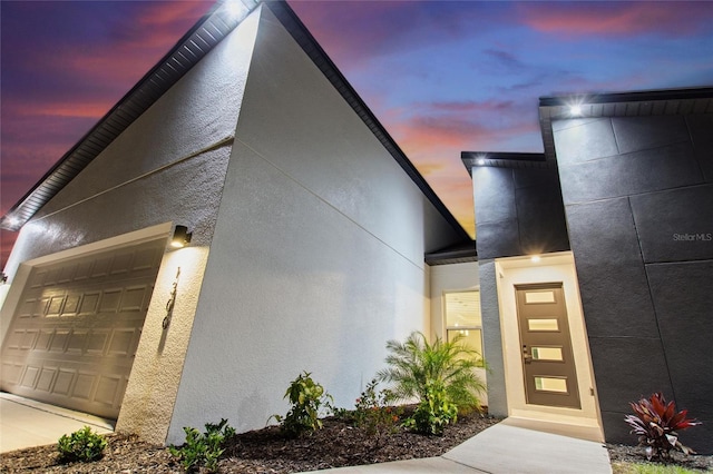 entrance to property with a garage and stucco siding