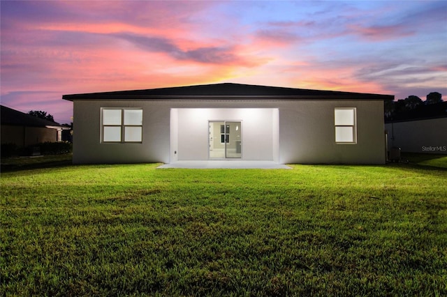 back of property with a patio area, a lawn, and stucco siding