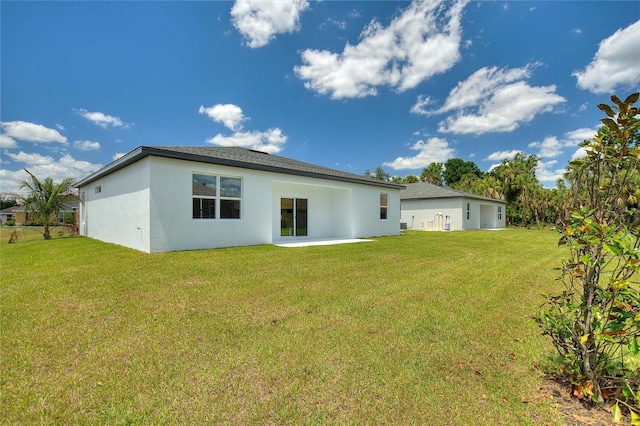 back of house featuring a yard, a patio area, and stucco siding