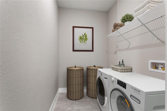 washroom with baseboards, laundry area, a textured wall, and washer and dryer