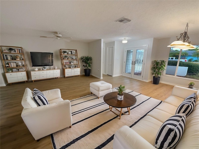 living area with baseboards, french doors, visible vents, and light wood-style floors