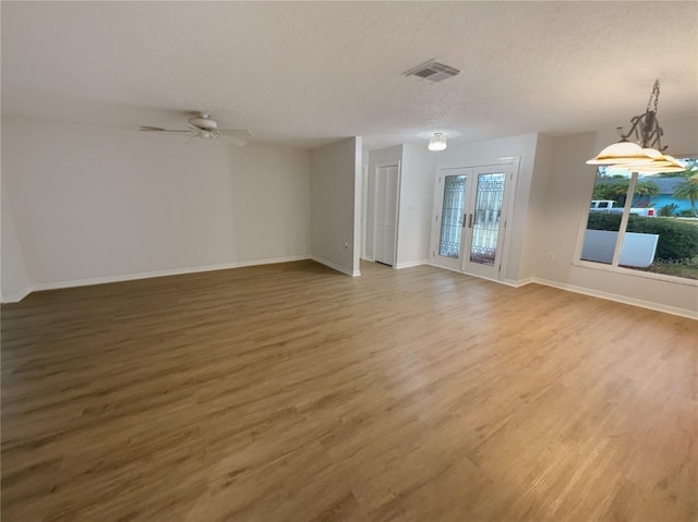 spare room featuring a textured ceiling, wood finished floors, visible vents, baseboards, and french doors