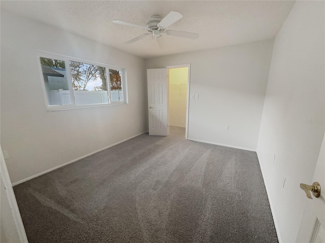 spare room with carpet flooring, ceiling fan, a textured ceiling, and baseboards