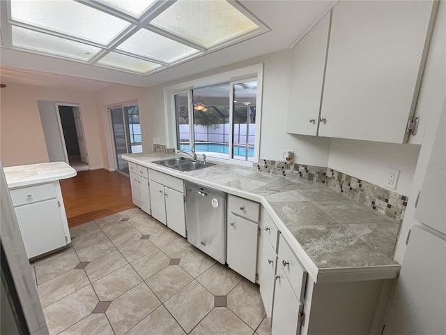 kitchen featuring white cabinets, dishwasher, a peninsula, and a sink