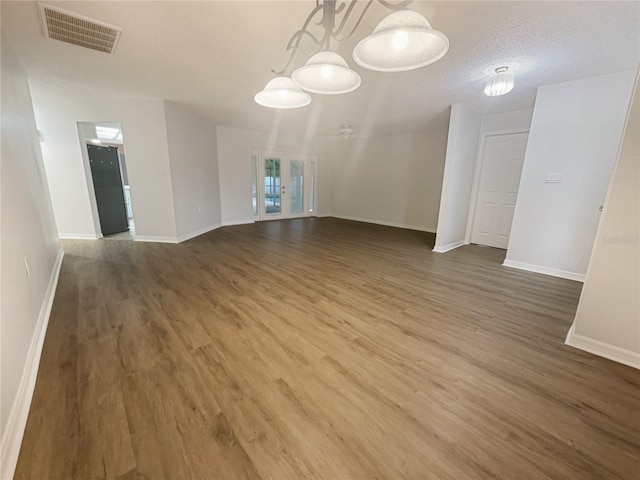 interior space with visible vents, dark wood finished floors, a textured ceiling, and baseboards