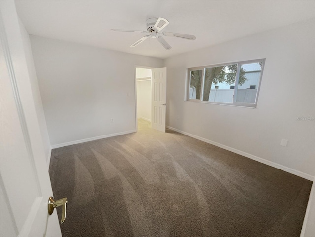 carpeted empty room with ceiling fan and baseboards