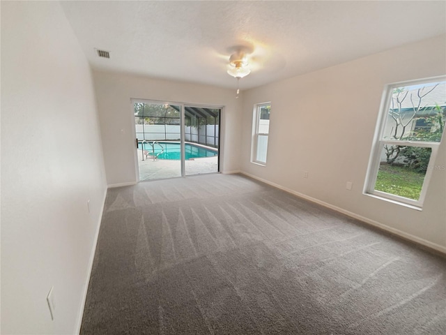 empty room with carpet floors, visible vents, and baseboards