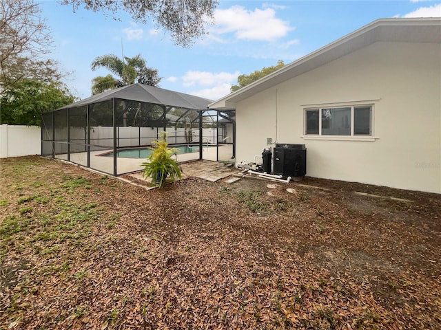 view of yard with glass enclosure, fence, a fenced in pool, and a patio