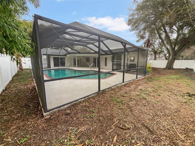 view of pool with glass enclosure, a patio area, a fenced backyard, and a fenced in pool