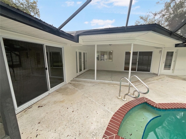 exterior space with a patio area, glass enclosure, an outdoor pool, and stucco siding