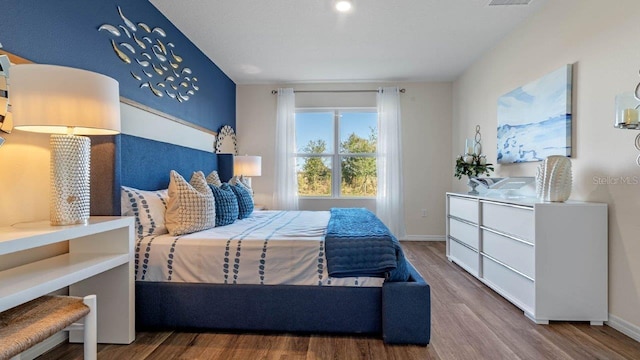 bedroom featuring wood finished floors, visible vents, and baseboards