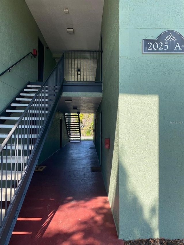 hall with stairway, concrete flooring, a textured wall, and a towering ceiling