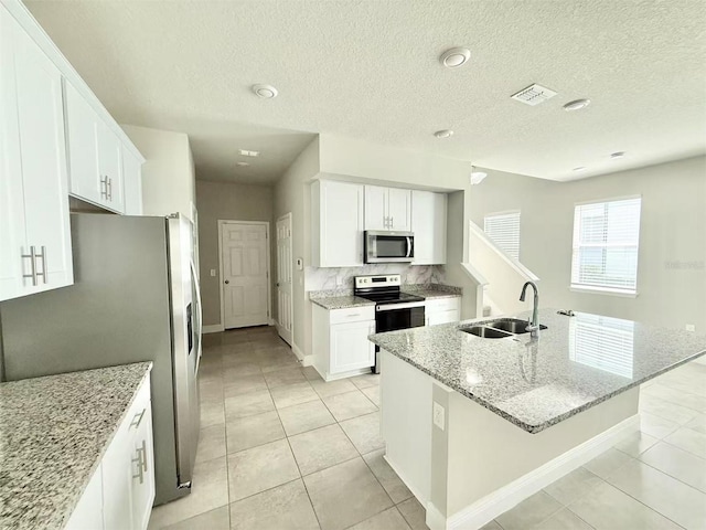 kitchen with stainless steel appliances, a sink, white cabinetry, visible vents, and light stone countertops