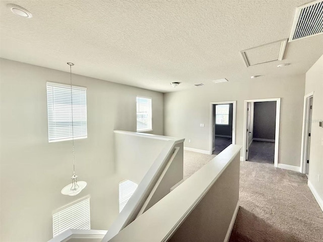 corridor featuring carpet, baseboards, visible vents, and an upstairs landing