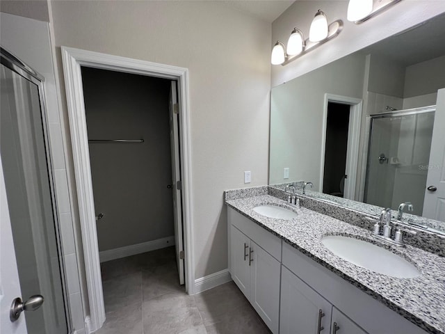 bathroom with double vanity, a stall shower, a sink, and baseboards