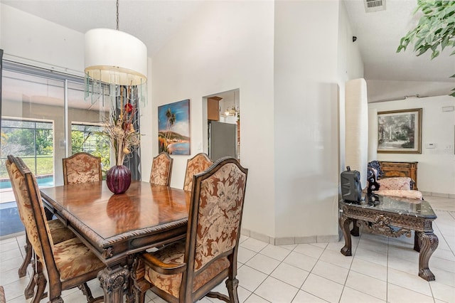 dining space featuring baseboards, visible vents, a textured ceiling, high vaulted ceiling, and light tile patterned flooring