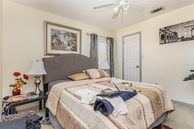 carpeted bedroom with a ceiling fan, visible vents, a textured ceiling, and baseboards