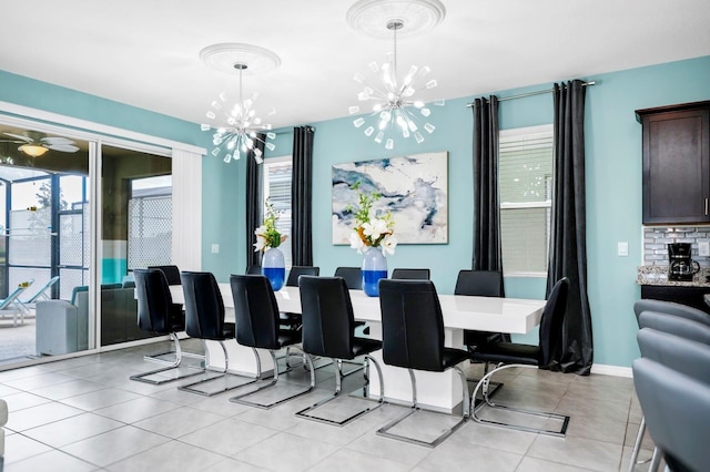 dining area with ceiling fan with notable chandelier, light tile patterned flooring, and baseboards